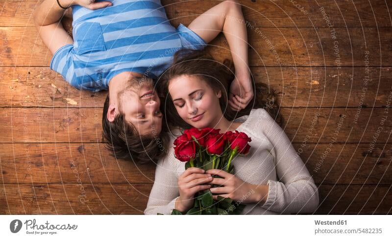 Junges verliebtes Paar auf Holzboden liegend hölzern Freizeit Muße Liebespaar Liebespaare Oberkörper Oberkörperaufnahmen Halbfigur kopfüber auf dem Kopf