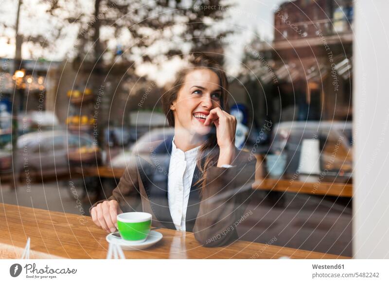 Lächelnde junge Frau in einem Cafe Kaffeehaus Bistro Cafes Café Cafés Kaffeehäuser Fenster weiblich Frauen lächeln Gastronomie Getränk Getraenk Getränke
