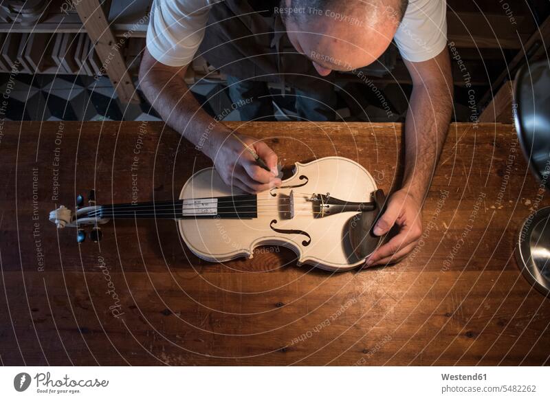 Luthier beim Einstellen des Stimmstocks einer unlackierten Geige in seiner Werkstatt Violine Geigen Violinen Werkstätte Werkstaette Werkstaetten Werkstätten