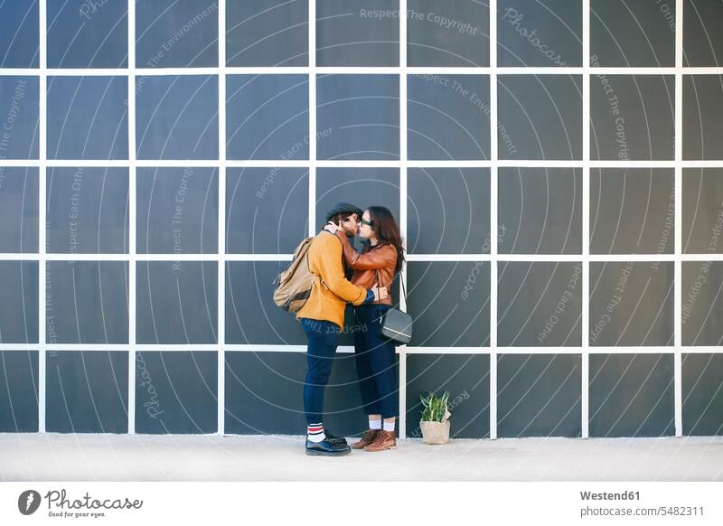 Küssendes junges Paar küssen Kuss Pärchen Paare Partnerschaft Mensch Menschen Leute People Personen gegenüber gegenueber stehen stehend steht verliebt Wand