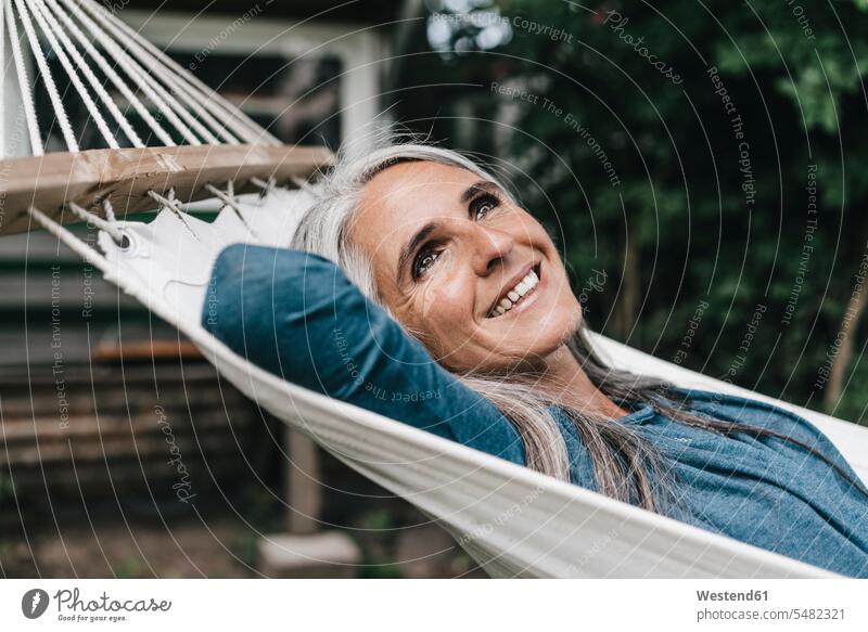 Porträt einer lächelnden Frau, die in der Hängematte im Garten liegt Hängematten weiblich Frauen glücklich Glück glücklich sein glücklichsein Erwachsener