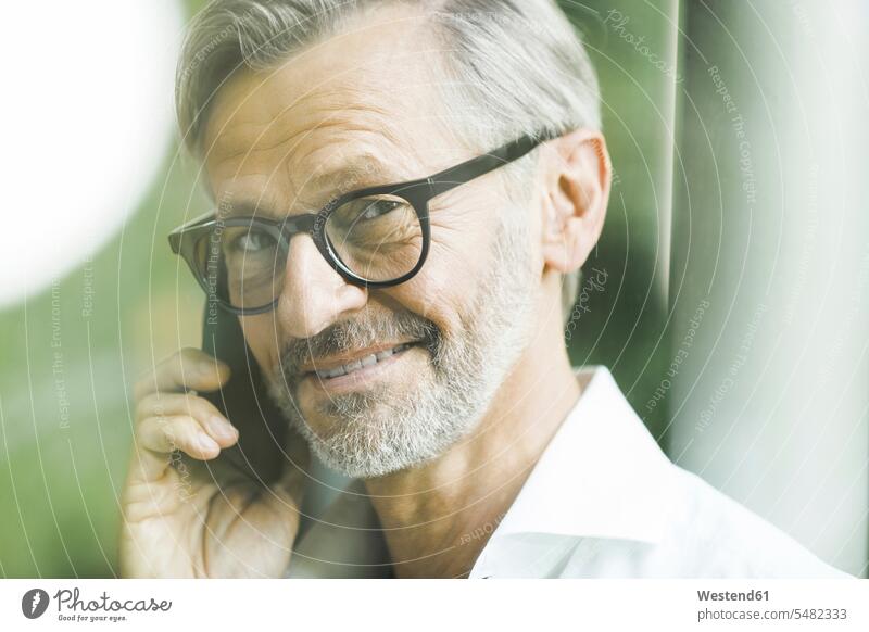 Porträt eines lächelnden Mannes mit grauen Haaren und Bart am Telefon Männer männlich Portrait Porträts Portraits Smartphone iPhone Smartphones telefonieren