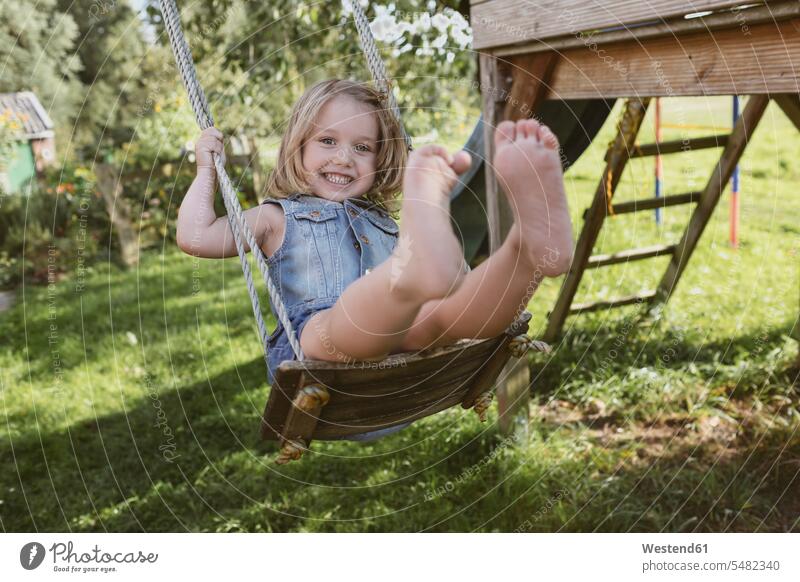 Glückliches kleines Mädchen auf der Schaukel im Garten weiblich Schaukeln schaukeln schwingen Kind Kinder Kids Mensch Menschen Leute People Personen lachen