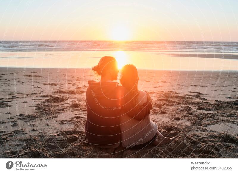 Portugal, Algarve, Ehepaar sitzt bei Sonnenuntergang am Strand glücklich Glück glücklich sein glücklichsein Beach Straende Strände Beaches sitzen sitzend Paar