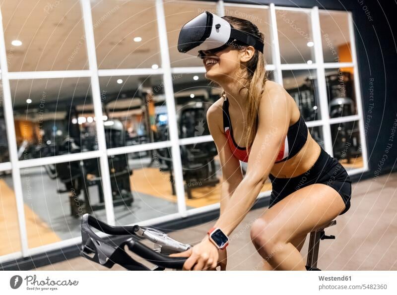Frau mit VR-Brille auf Spinning Bike in der Turnhalle weiblich Frauen Virtual Reality Brille Virtual-Reality-Brille Virtual Reality-Brille VR Brille