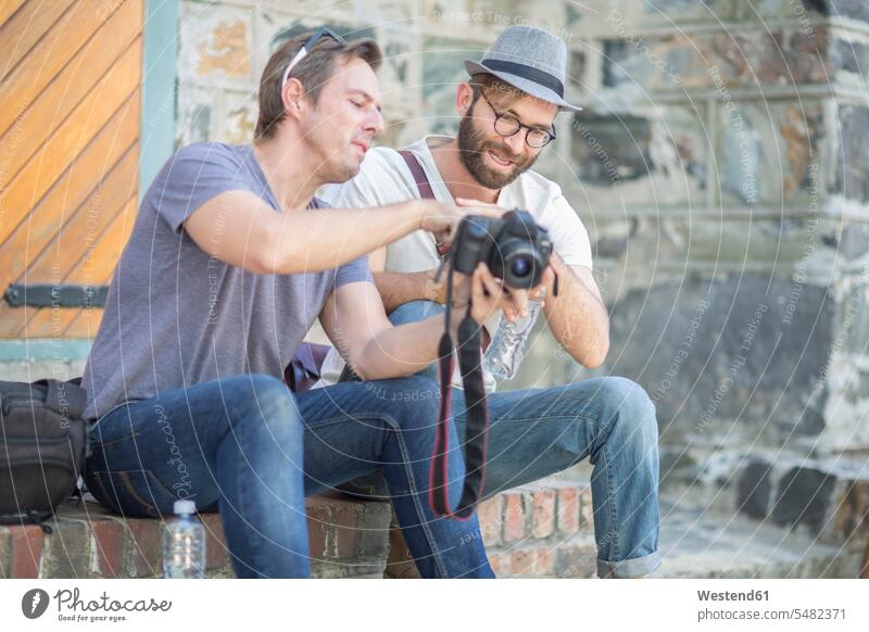 Zwei Männer mit Kamera im Freien Mann männlich Fotoapparat Fotokamera Erwachsener erwachsen Mensch Menschen Leute People Personen Tourist Touristen sitzen
