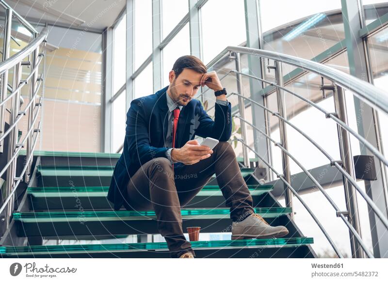Nachdenklicher Geschäftsmann sitzt auf der Treppe und schaut auf sein Handy Businessmann Businessmänner Geschäftsmänner Nachricht Mitteilung Botschaft