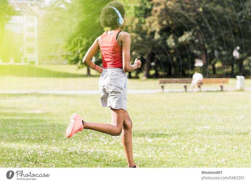 Junge Frau mit Kopfhörern läuft im Park Parkanlagen Parks laufen rennen trainieren weiblich Frauen Kopfhoerer Joggen Jogging Erwachsener erwachsen Mensch