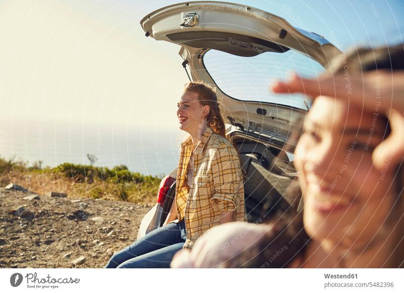Südafrika, Kapstadt, Signal Hill, zwei glückliche junge Frauen an einem Auto an der Küste Kueste Kuesten Küsten Wagen PKWs Automobil Autos weiblich lachen