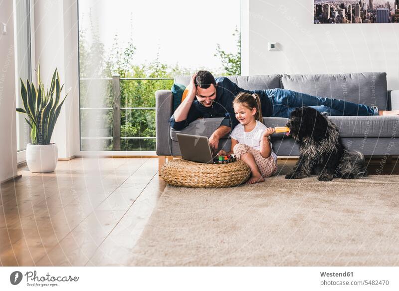 Vater benutzt Laptop zu Hause mit seiner kleinen Tochter Papas Väter Vati Vatis Papis Hund Hunde Zuhause daheim Töchter Notebook Laptops Notebooks lernen Eltern