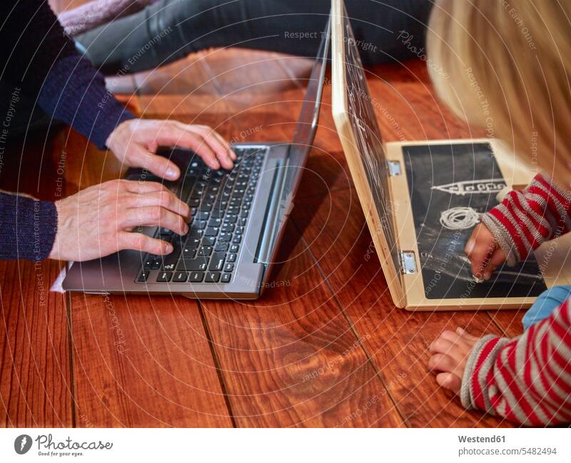Vater mit Laptop auf dem Boden sitzend, Tochter zeichnet auf Spielzeug-Laptop Europäer Kaukasier Europäisch kaukasisch Nachahmung nachahmen Imitation imitieren