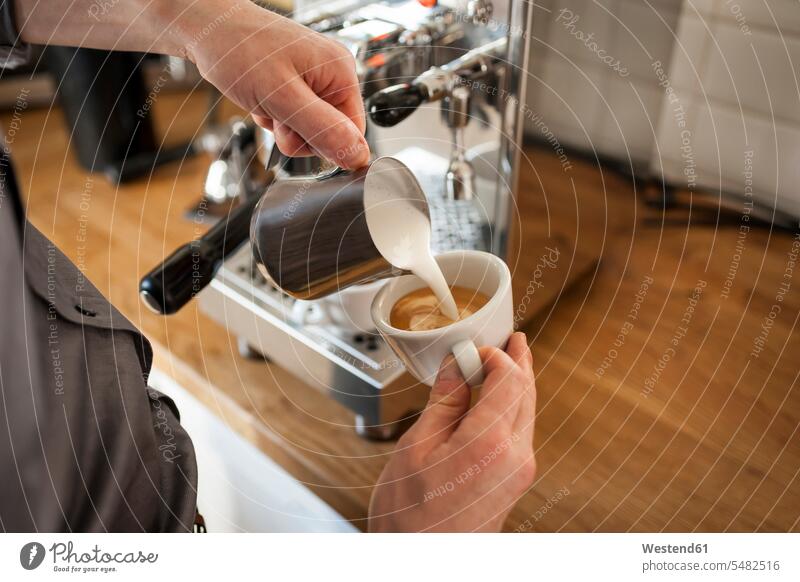 Cappuccino, Mann giesst Milchschaum in Kaffeetasse Perfektion Vollkommenheit Vollendung vollkommen perfekt vollendet Milchkanne Milchkannen Maschine Maschinen