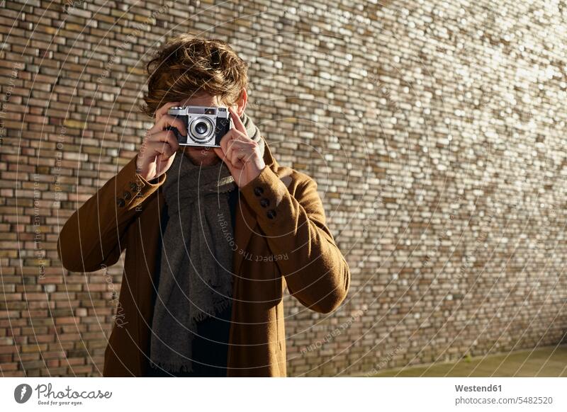Junger Mann beim Fotografieren eines Zuschauers mit einer Oldtimer-Kamera Europäer Kaukasier Europäisch kaukasisch Köln Oberkörper Oberkörperaufnahmen Halbfigur