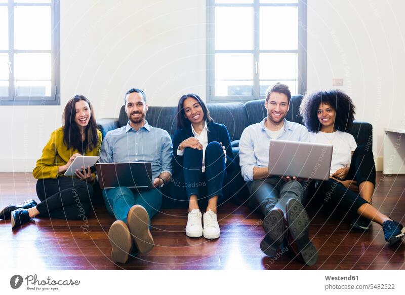 Porträt von glücklichen Kollegen, die mit Laptops auf der Couch sitzen Büro Office Büros Arbeitsplatz Arbeitsstätte Arbeitstelle Arbeitskollegen Notebook