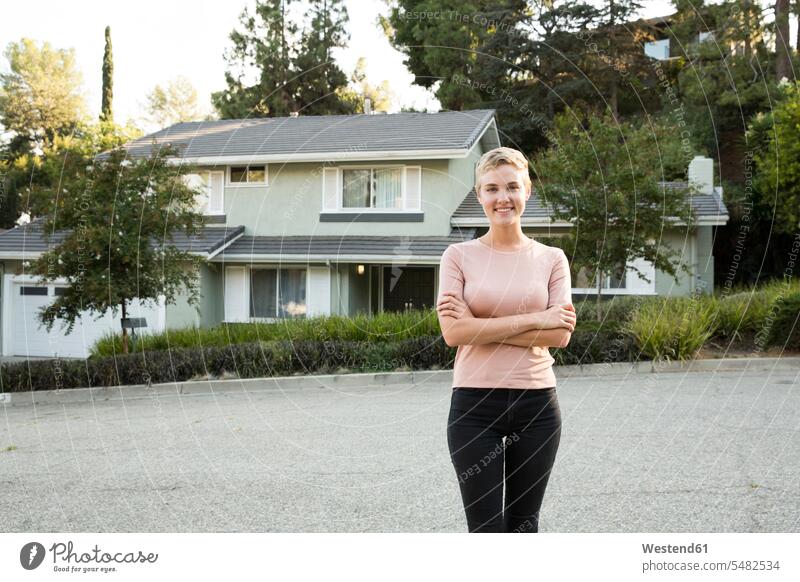 Porträt einer lächelnden Frau vor ihrem Haus weiblich Frauen Portrait Porträts Portraits Häuser Haeuser Zuversicht Zuversichtlich Selbstvertrauen selbstbewusst