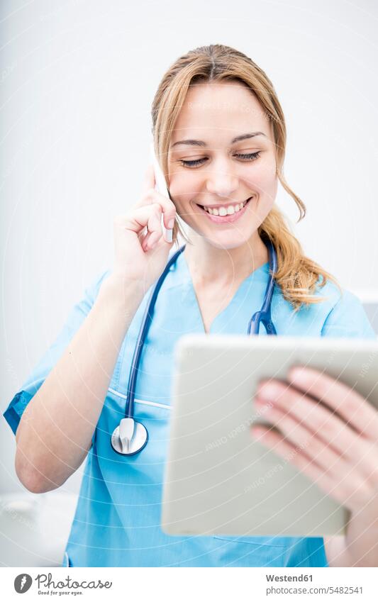 Lächelnder Arzt am Telefon sieht Tablette an Handy Mobiltelefon Handies Handys Mobiltelefone Frau weiblich Frauen lächeln Ärztin Aerztin Ärztinnen Doktorinnen