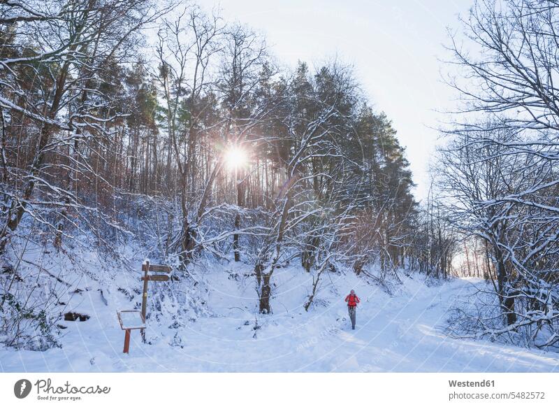 Deutschland, Nordrhein-Westfalen, Nationalpark Eifel, Mann wandert in schneebedeckter Landschaft Abendstimmung Freizeitkleidung casual Freizeitbekleidung