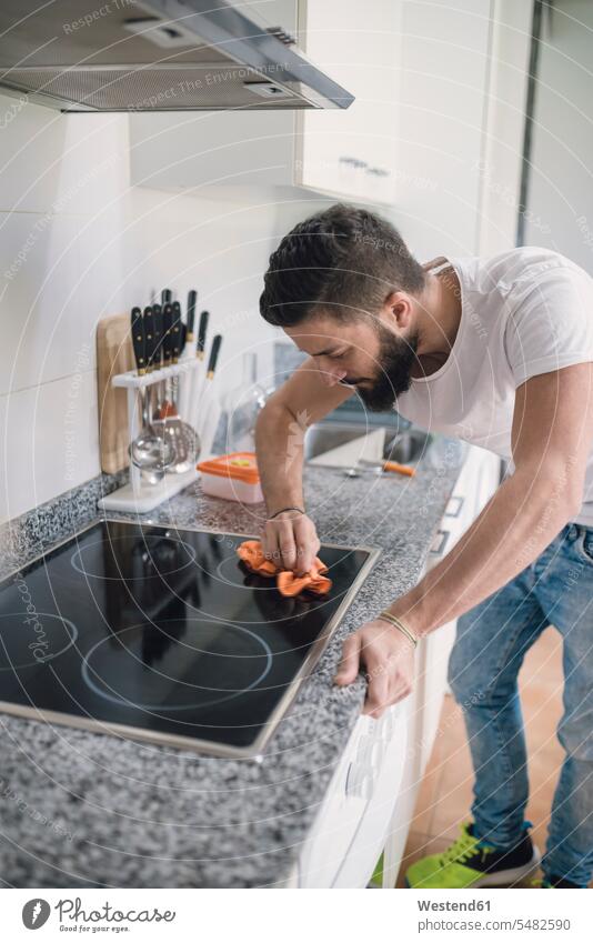 Junger Mann reinigt Keramikkochfeld Männer männlich Reinigen putzen Saubermachen Küche Erwachsener erwachsen Mensch Menschen Leute People Personen Haushalt