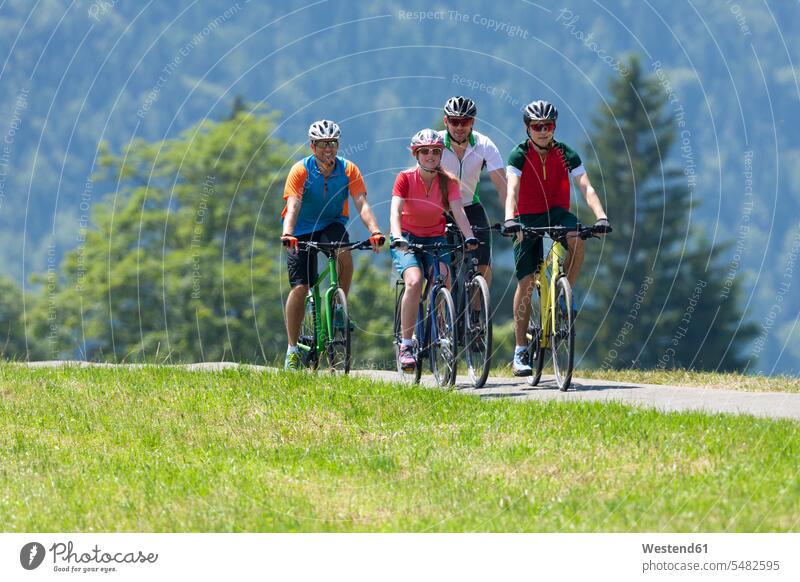 Vier Personen auf einer Fahrradtour mit Trekking-Fahrrädern Europäer Kaukasier Europäisch kaukasisch Wiese Wiesen Aktivität Aktivitaet aktiv Weg Wege Pfad Bikes