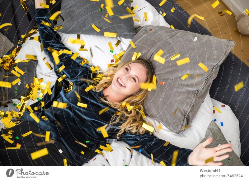 Porträt einer glücklichen jungen Frau mit fliegendem Konfetti zu Hause Zuhause daheim Portrait Porträts Portraits Spaß Spass Späße spassig Spässe spaßig