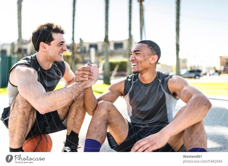 Zwei junge Männer schütteln sich die Hände auf dem Basketballplatz Europäer Kaukasier Europäisch kaukasisch fit multikulturell Freunde Vergnügen genießen freuen