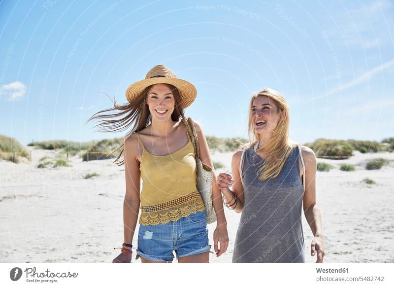 Zwei glückliche Freundinnen am Strand lächeln Frau weiblich Frauen Urlaub Ferien Beach Straende Strände Beaches Freunde Freundschaft Kameradschaft Erwachsener