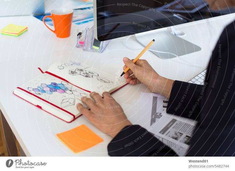 Frau zieht am Schreibtisch im Büro in ein Notizbuch Notizbücher Notizbuecher Arbeitstisch Schreibtische zeichnen Zeichnung Office Büros Tisch Tische