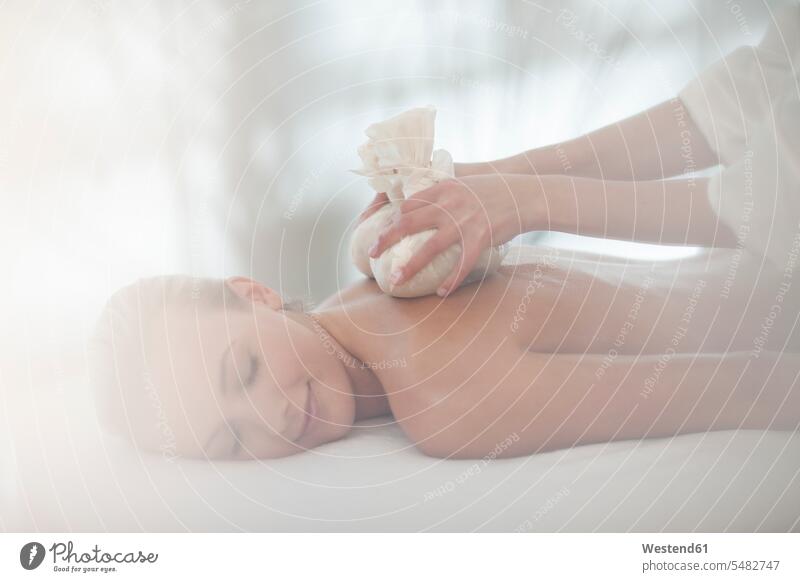 Masseurin legt Aromatherapiebeutel auf den Rücken der Frau Beutel Wellness Gesundheit Massage Massagen massieren weiblich Frauen liegen liegend liegt Spa