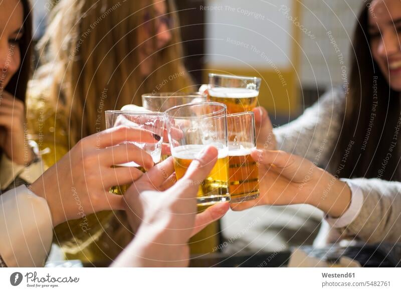 Freunde stoßen mit Biergläsern in einem Straßencafé an, Nahaufnahme Europäer Kaukasier Europäisch kaukasisch anstoßen zuprosten anstossen Zufriedenheit