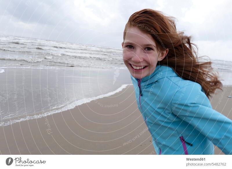 Porträt eines lächelnden rothaarigen Mädchens an einem windigen Tag am Strand eine Person single 1 ein Mensch einzelne Person Ein nur eine Person Wind Windstoß