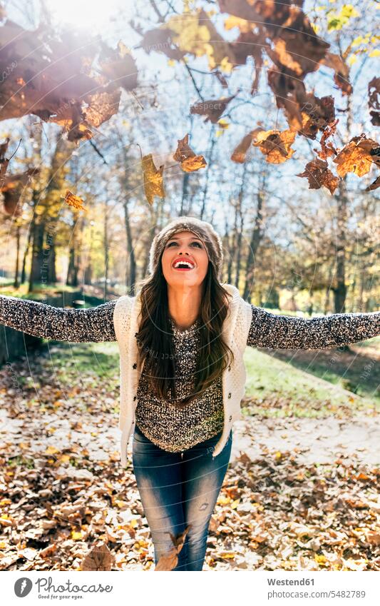 Schöne glückliche Frau amüsiert sich mit Blättern in einem herbstlichen Wald weiblich Frauen Portrait Porträts Portraits Herbst Spaß Spass Späße spassig Spässe