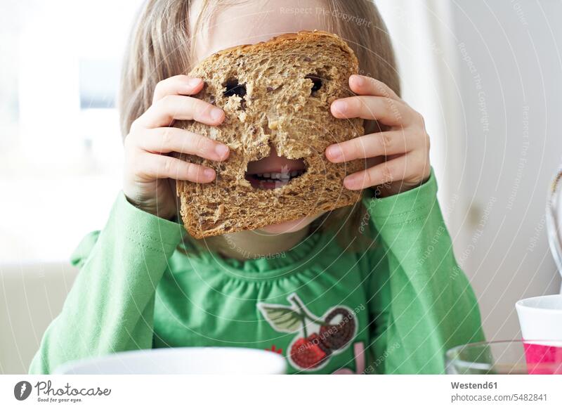 Kleines Mädchen schaut durch Löcher in Brotscheibe Brote Kind Kinder Kids Essen Food Food and Drink Lebensmittel Essen und Trinken Nahrungsmittel Mensch