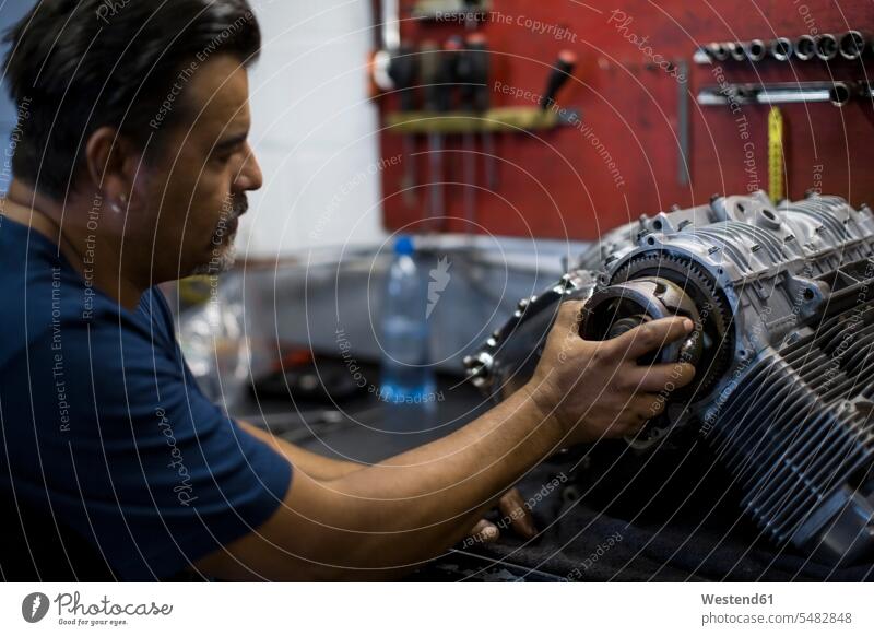 Mechaniker, der in der Werkstatt am Motorradmotor arbeitet Motoren arbeiten Arbeit Monteur reparieren Reparatur Industrie industriell Gewerbe Industrien