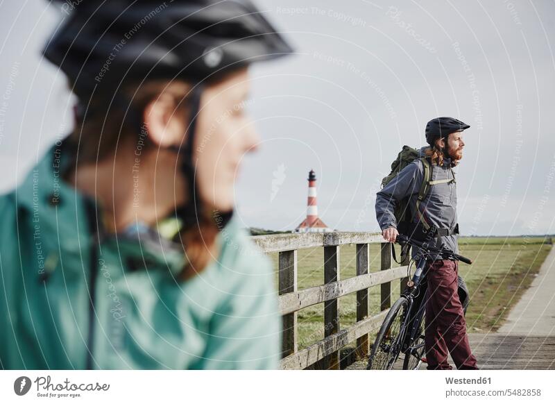 Deutschland, Schleswig-Holstein, Eiderstedt, Ehepaar auf Fahrradtour mit Pause in der Nähe des Leuchtturms von Westerheversand Paar Pärchen Paare Partnerschaft