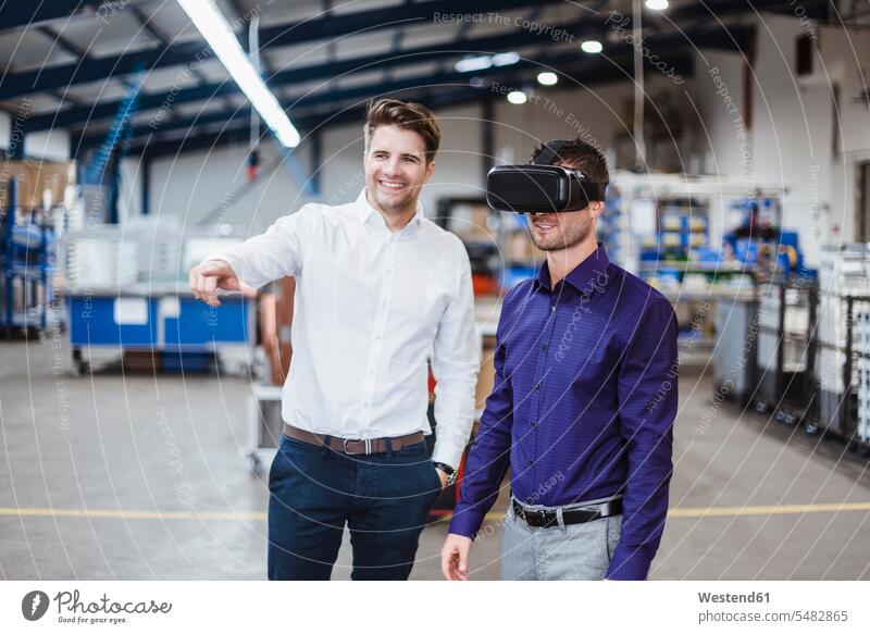 Zwei Mitarbeiter haben eine Besprechung, einer trägt eine VR-Brille Produktionshalle Montagehalle Angestellter Arbeitsbesprechung Briefing