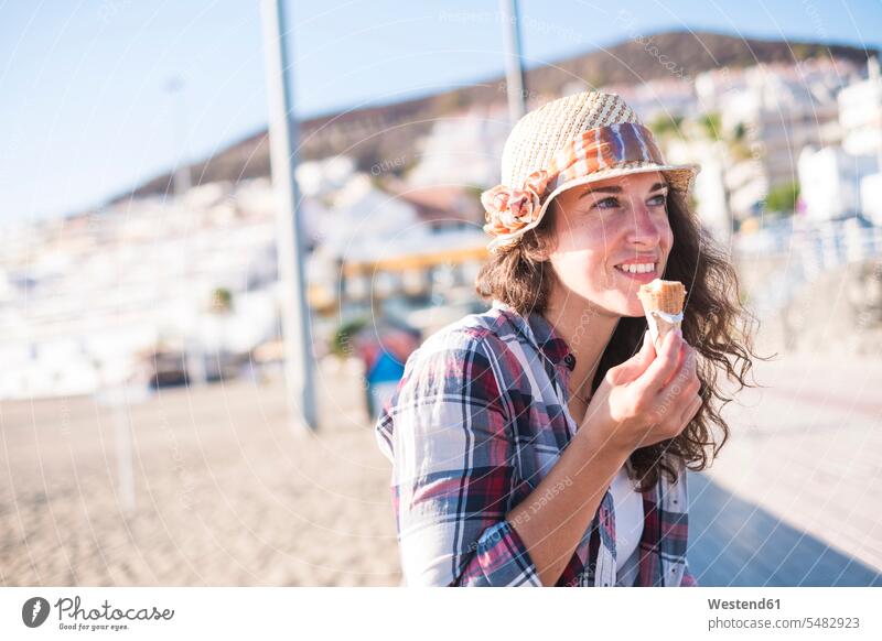 Junge Frau isst Eis am Strand weiblich Frauen essen essend Urlaub Ferien Eiscreme Speiseeis Sommer Sommerzeit sommerlich Erwachsener erwachsen Mensch Menschen