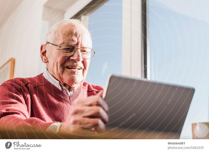 Älterer Mann sitzt zu Hause und benutzt Laptop Notebook Laptops Notebooks benutzen benützen Rentner Pensionär Pensionäre Online Websurfen Im Net surfen Surfen