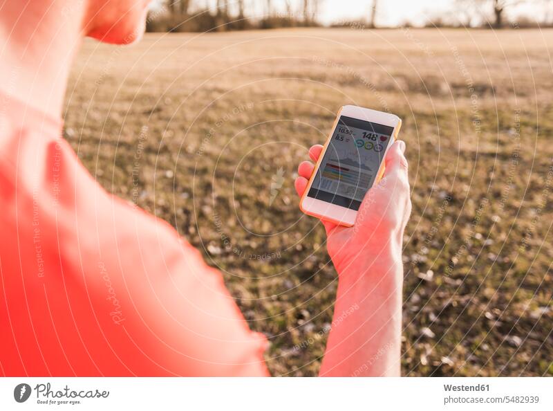 Sportler in ländlicher Landschaft überprüft Daten auf Mobiltelefon Joggen Jogging Mann Männer männlich Handy Handies Handys Mobiltelefone Fitness fit Gesundheit