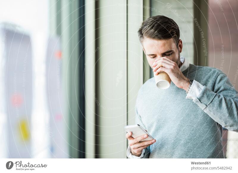 Junger Mann mit Kaffee zum Handy anschauen Europäer Kaukasier Europäisch kaukasisch Nachricht Mitteilung Botschaft Information Informationen Deutschland