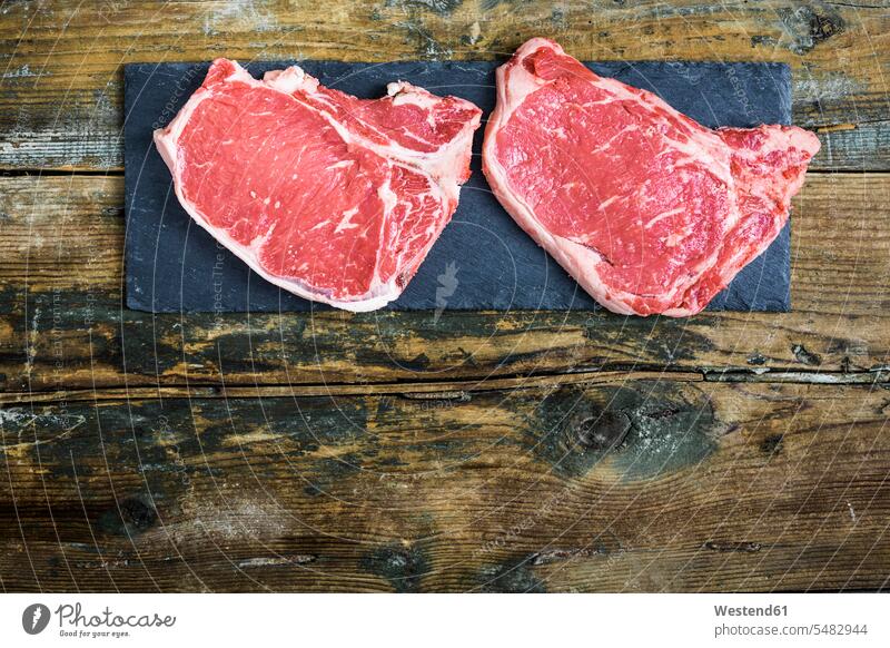 Rohe Beefsteaks Rindfleisch T-bone Steak T-bone-Steak T bone Steak Zutaten Steaks Schiefer Schieferstein Schiefersteine Holz hoelzern hölzern Porterhouse Steak