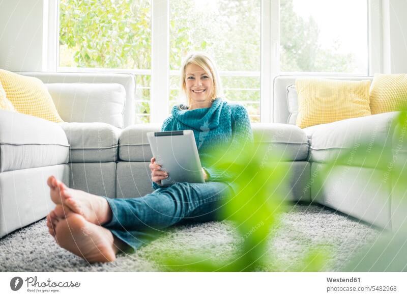 Porträt einer glücklichen Frau mit Tablette im Wohnzimmer Portrait Porträts Portraits lächeln Tablet Computer Tablet-PC Tablet PC iPad Tablet-Computer weiblich