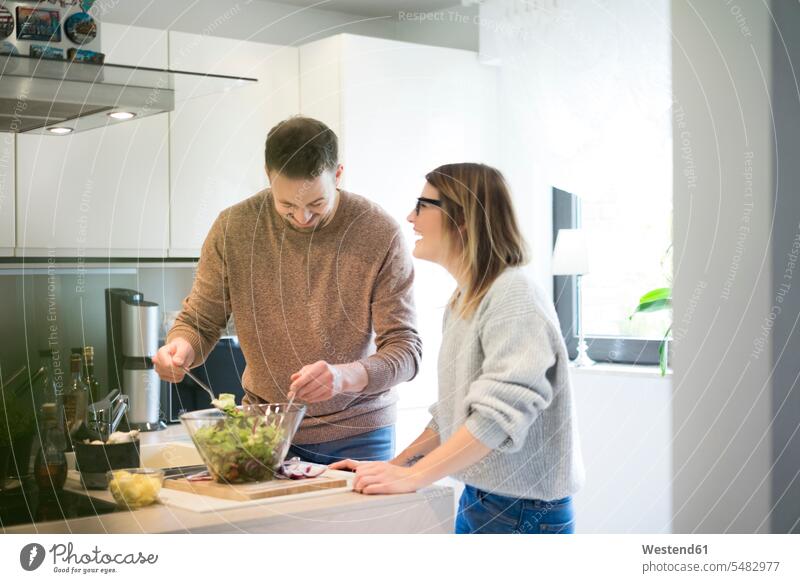 Glückliches Paar bereitet gemeinsam Salat in der Küche zu Pärchen Paare Partnerschaft Salate glücklich glücklich sein glücklichsein Zuhause zu Hause daheim