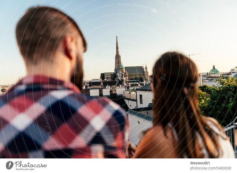 Österreich, Wien, Rückansicht eines jungen Paares auf der Dachterrasse mit Blick auf den Stephansdom Europäer Kaukasier Europäisch kaukasisch