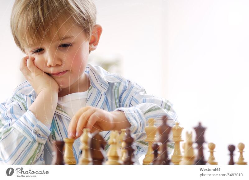 Porträt eines denkenden kleinen Jungen beim Schachspielen ratlos hilflos Hilflosigkeit Zweifel Bedenken zweifeln Können Fähigkeit Fertigkeit Könnerschaft ernst