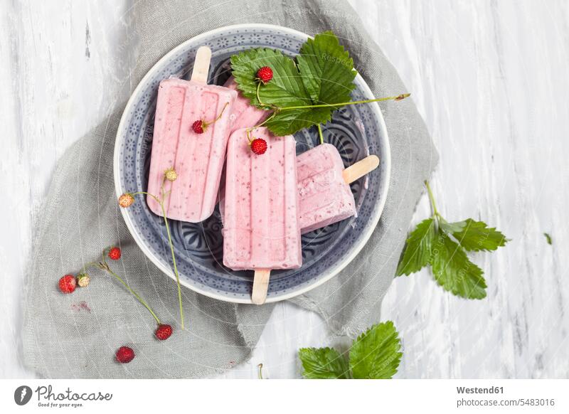 Hausgemachte Erdbeereis-Lollies mit Chia auf Teller Schüssel Schalen Schälchen Schüsseln Eis am Stiel Steckerleis Stieleis gefroren vereist eingefroren
