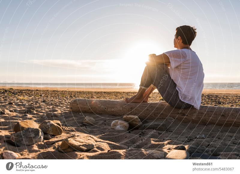 Frankreich, Bretagne, Halbinsel Crozon, Frau sitzt bei Sonnenuntergang am Strand genießen geniessen Genuss Strandspaziergang Sonnenuntergänge Beach Straende