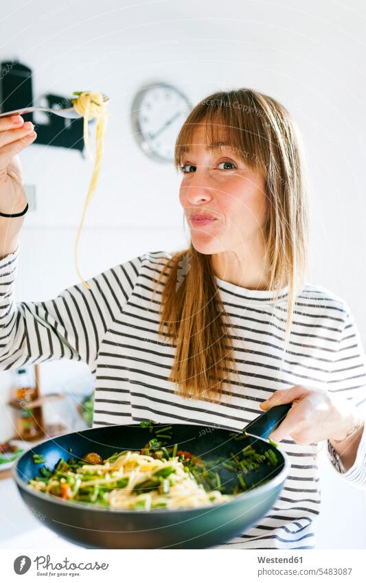 Junge Frau hält Pfanne mit veganem Nudelgericht weiblich Frauen kochen Zuhause zu Hause daheim vegetarisch Vegetarische Nahrung Vegetarische Ernährung
