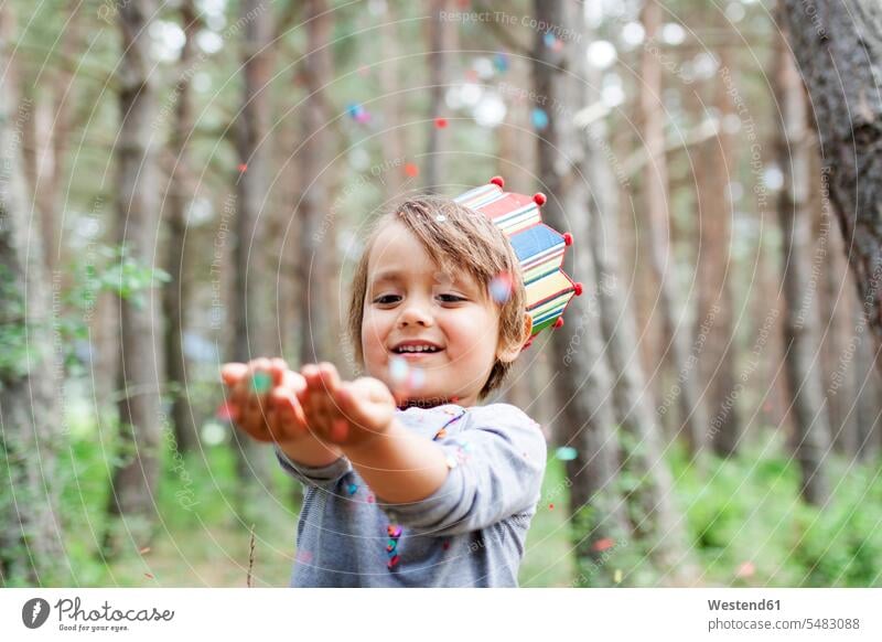 Porträt eines lächelnden kleinen Jungen mit Papierkrone, der Konfetti fängt fangen fangend Freude freuen Confetti Kindergeburtstag Kindergeburtstagsfeier