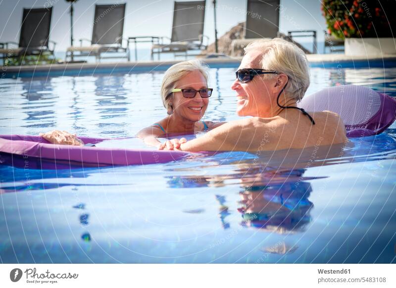 Glückliches Seniorenpaar im Schwimmbad Urlaubsort Ferienort Resort Urlaubsresort Erholungsort Entspannung relaxen entspannen Freude freuen lächeln