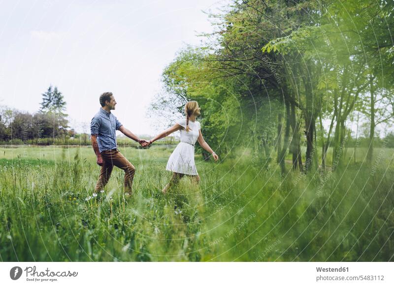 Verliebtes Paar hält sich beim Spaziergang auf einer Wiese an den Händen Italien ländliches Motiv nicht städtisch Zweisamkeit Naturverbundenheit naturverbunden